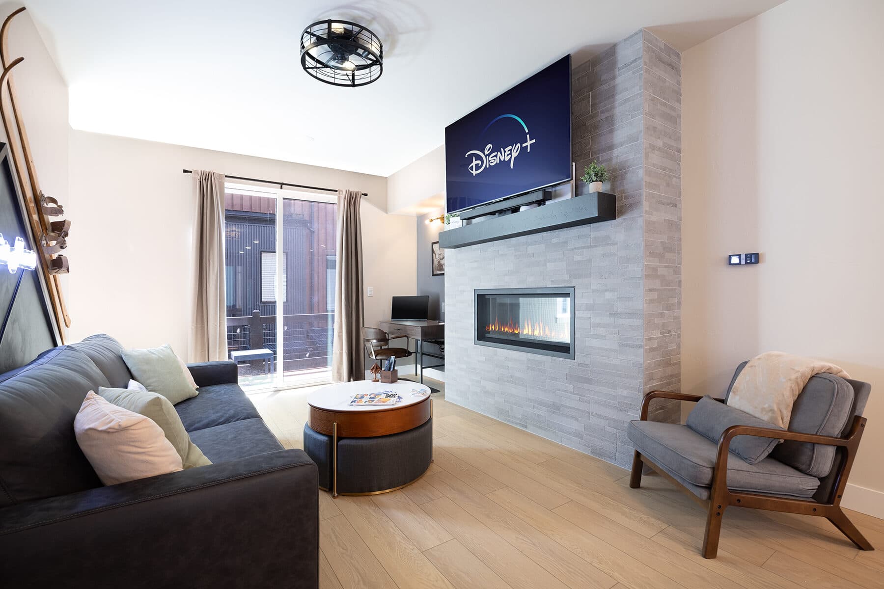 Bright open-concept great room with a fireplace and mountain-view windows at the Après Haus